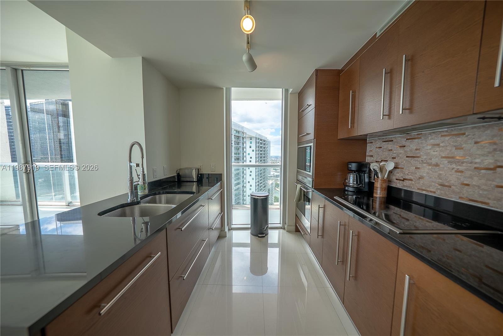 Icon Brickell Miami, FL 33131 - Photo 14 of 26 a kitchen with kitchen island granite countertop a sink stove and cabinets
