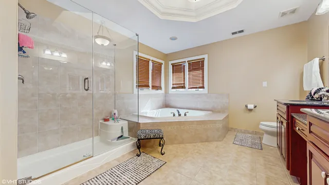 a spacious bathroom with a bathtub shower sink mirror and toilet