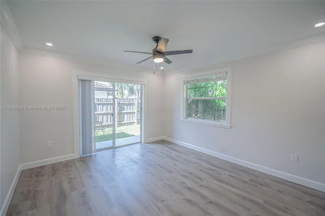 an empty room with wooden floor chandelier fan and windows