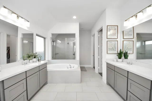 a spacious bathroom with a double vanity sink a large mirror and a bathtub