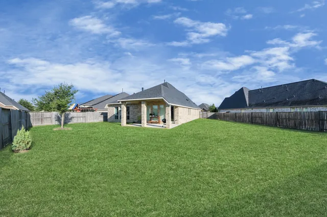a yellow and red house with a big yard and large trees