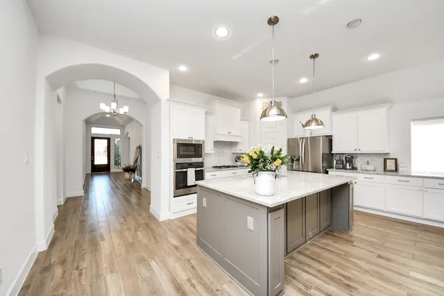 a large kitchen with kitchen island a sink and a refrigerator
