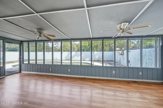 a view of empty room with wooden floor and fan