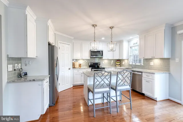 a kitchen with granite countertop a refrigerator a sink a stove a dining table and chairs