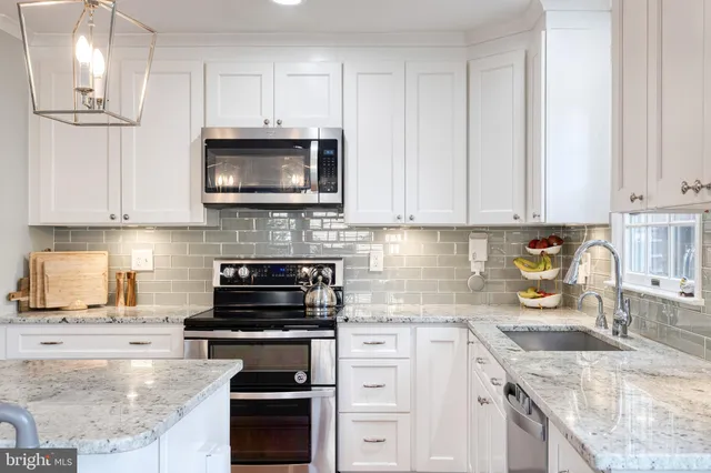 a kitchen with stainless steel appliances granite countertop white cabinets sink and stove