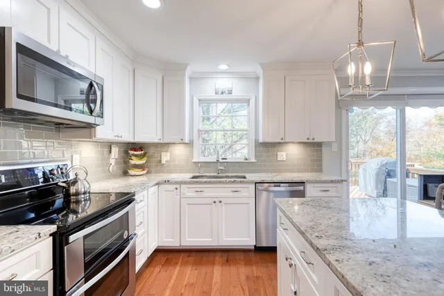 a kitchen with stainless steel appliances granite countertop wooden cabinets granite counter tops and a hard wood floors