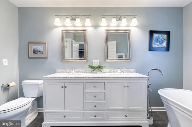 a bathroom with a granite countertop toilet a sink and a mirror