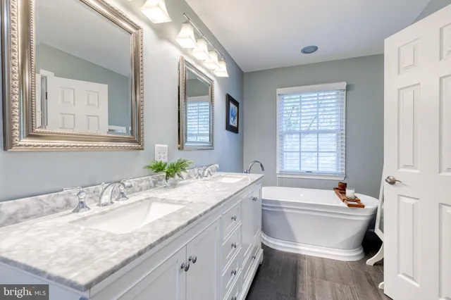 a bathroom with a granite countertop sink and a bathtub