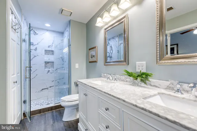a bathroom with a granite countertop sink toilet a large mirror a glass door and shower