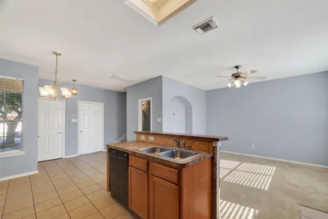 a kitchen that has a sink stainless steel appliances and chandelier