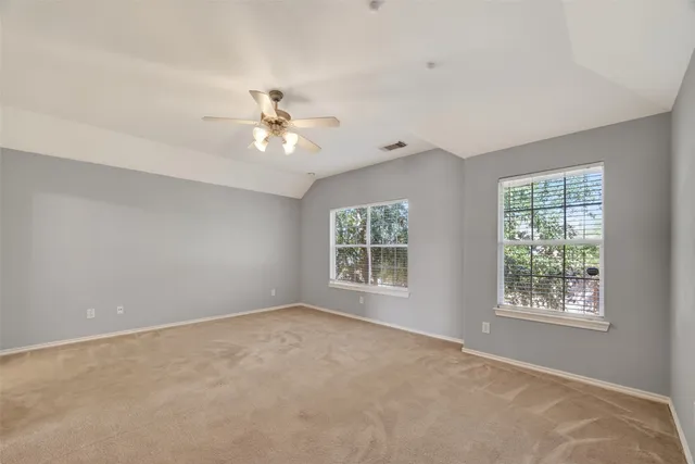 an empty room with windows and ceiling fan