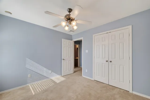 an empty room with kitchen view and a ceiling fan