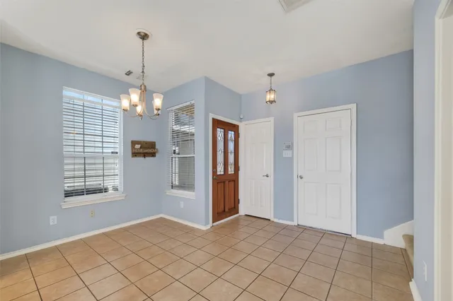 a view of an empty room with window and chandelier fan