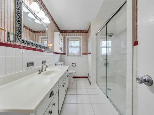 a spacious bathroom with a double vanity sink a mirror and a shower