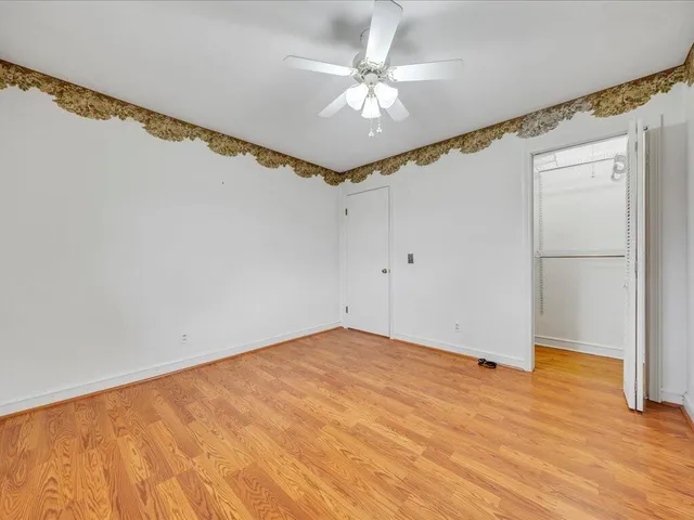 a view of a big room with wooden floor and chandelier fan