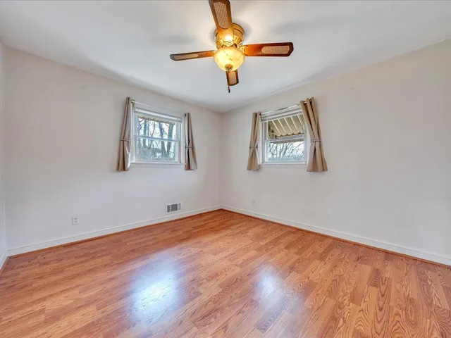 a view of an empty room with window and wooden floor