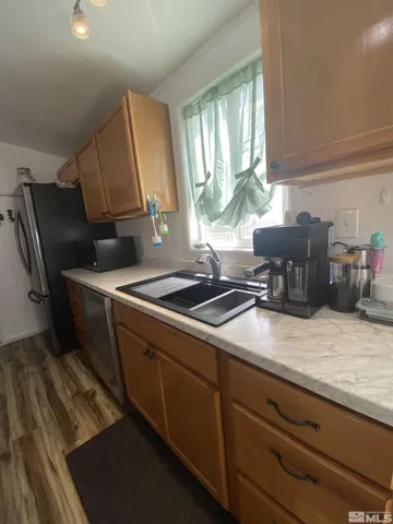 a kitchen with stainless steel appliances a sink dishwasher a stove a refrigerator white cabinets and wooden floor