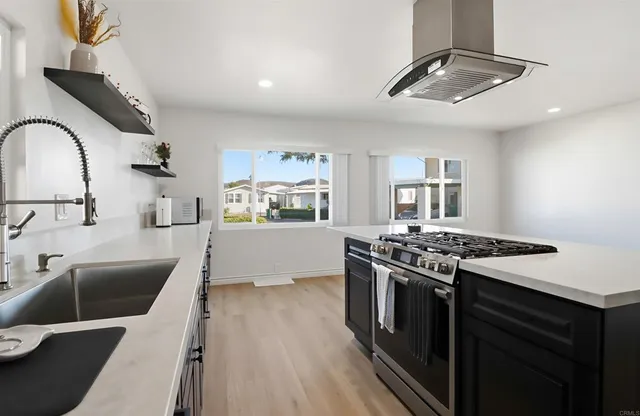 a kitchen with stainless steel appliances granite countertop a stove a sink dishwasher and a refrigerator with wooden floor