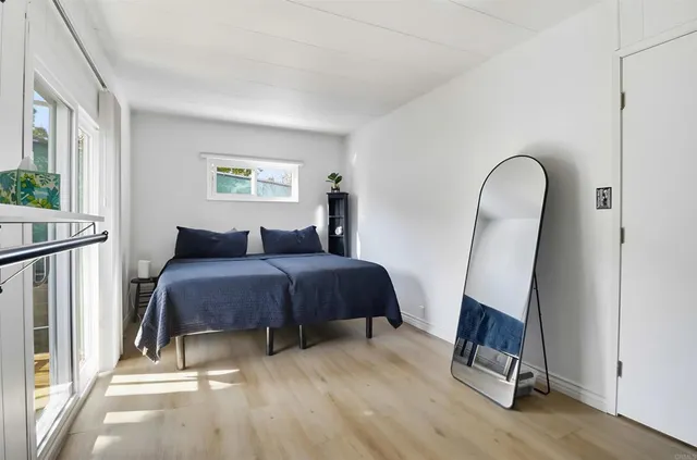 a bedroom with a bed a mirror and wooden floor
