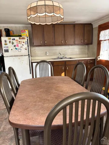 a kitchen with stainless steel appliances granite countertop a dining table chairs and a refrigerator