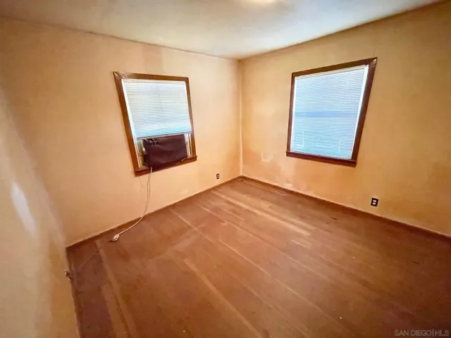 a view of an empty room with window and a dresser