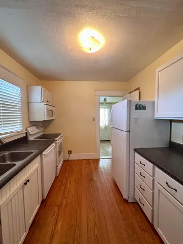 a kitchen with granite countertop a stove a sink and a microwave