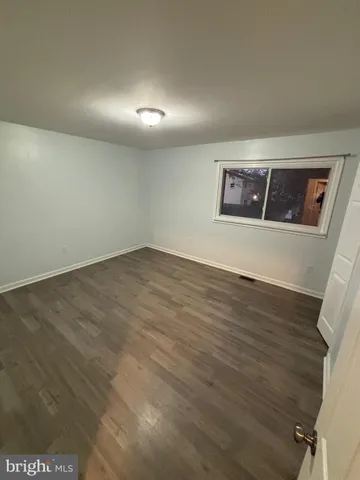 an empty room with wooden floor and window