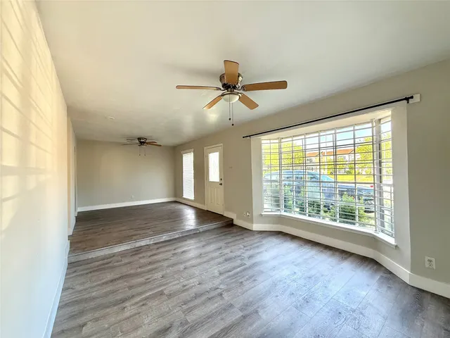 a view of an empty room with a window and wooden floor