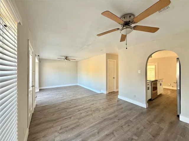 a view of a room with wooden floor a ceiling fan and windows