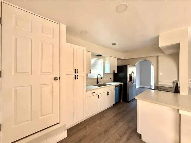 a large kitchen with a lot of counter space and wooden floor