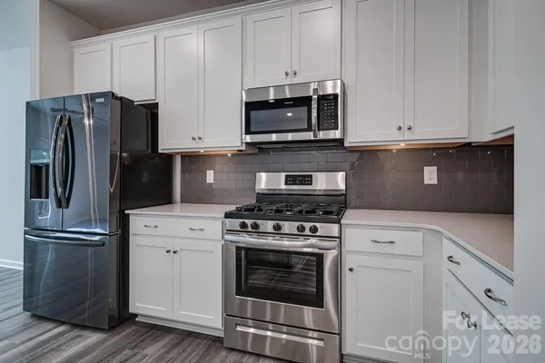 a kitchen with cabinets stainless steel appliances and wooden floor