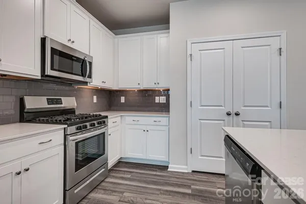 a kitchen with stainless steel appliances granite countertop a stove a microwave and a white cabinets