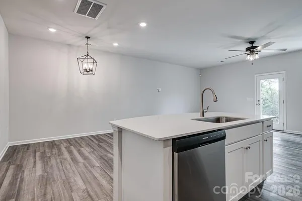 a kitchen with a sink dishwasher and white cabinets with wooden floor