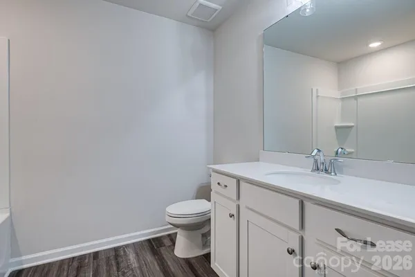 a bathroom with a granite countertop toilet sink and mirror