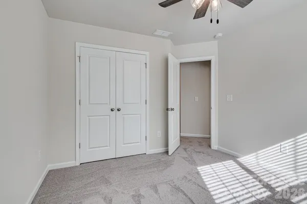 an empty room with closet and a chandelier fan