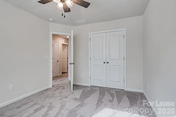 a view of an empty room and chandelier fan