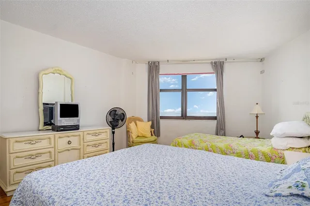 a bedroom with a bed and a flat tv screen on dresser