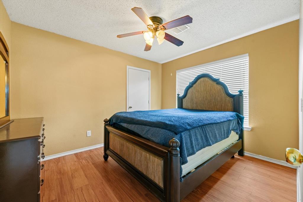 1818 Cedar Ridge Drive Mesquite, TX 75181 - Photo 17 of 21 Bedroom featuring light wood finished floors, ceiling fan, and a textured ceiling