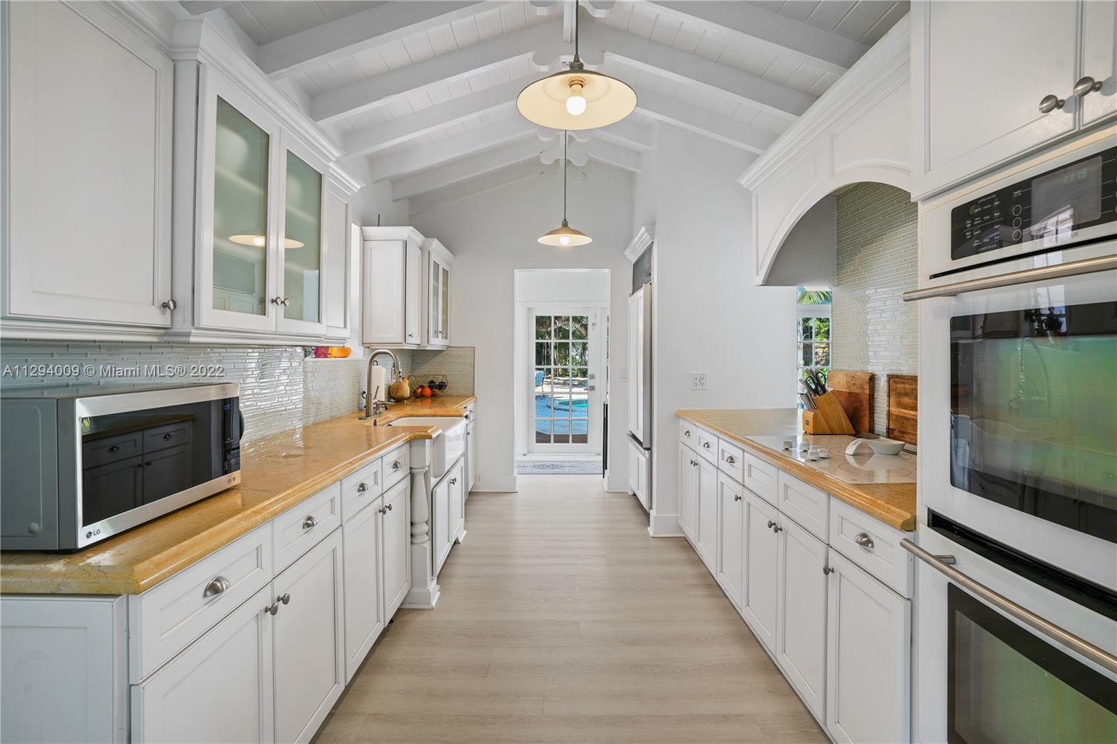 1701 Micanopy Avenue Miami, FL 33133 - Photo 11 of 46 a kitchen with stainless steel appliances a stove top oven a sink dishwasher and a microwave oven with white cabinets