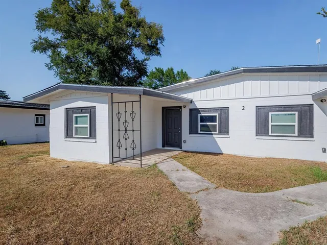 a front view of house with yard and trees in the background