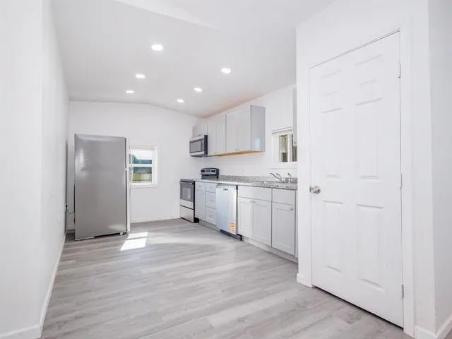 a view of a kitchen with a sink and dishwasher with white cabinets