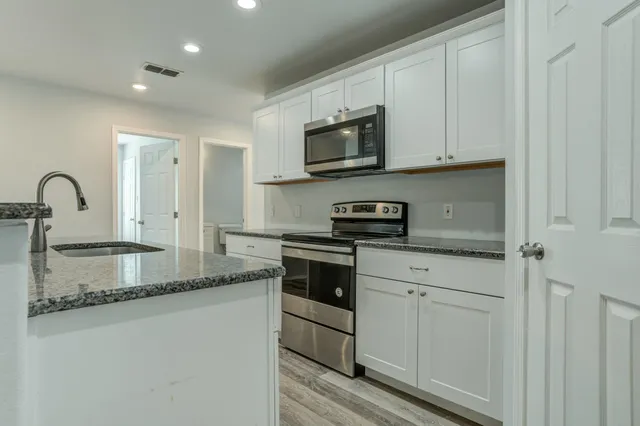 a kitchen with stainless steel appliances granite countertop a stove a sink and a microwave
