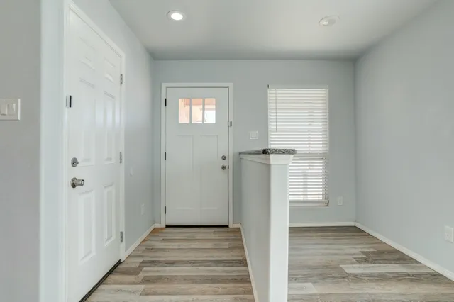 a view of a hallway with wooden floor and a bathroom