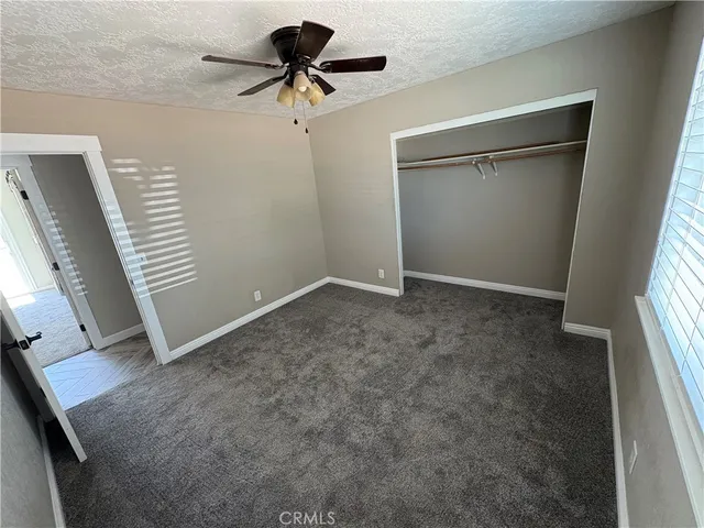 an empty room with windows and ceiling fan