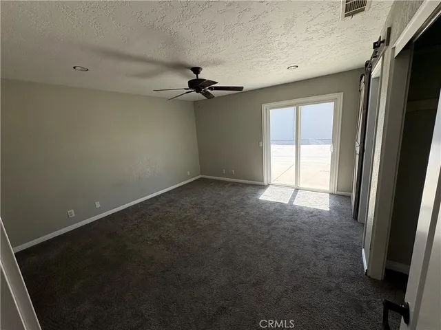 en empty room with windows and a ceiling fan