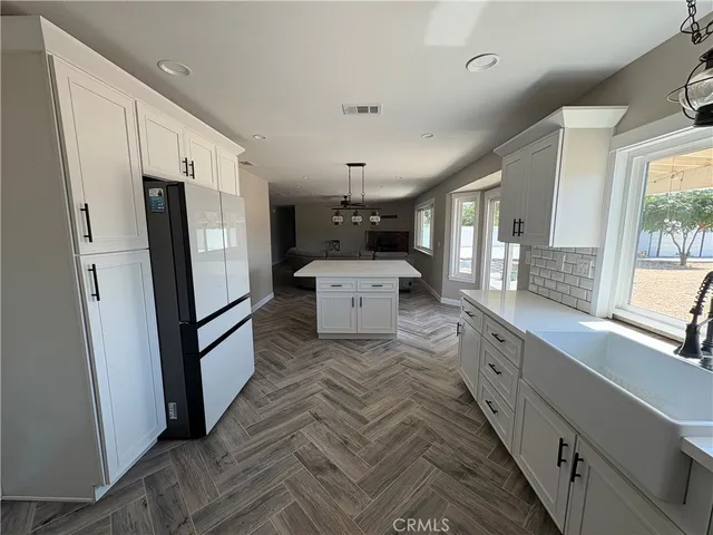 a large white kitchen with a refrigerator a sink stainless steel appliances and cabinets