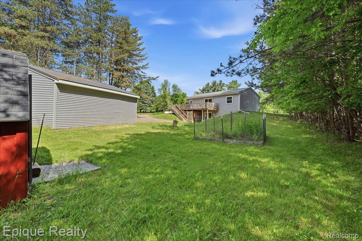 12272 East Mt Morris Road Davison, MI 48423 - Photo 35 of 39 Expansive rear yard featuring green lawn, mature trees, and a detached outbuilding with horizontal siding