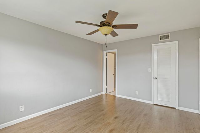a view of a room with wooden floor and a ceiling fan