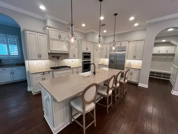 a kitchen with stainless steel appliances granite countertop a stove a refrigerator a kitchen island a dining table and chairs with wooden floor