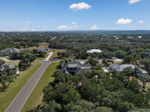 an aerial view of residential houses with outdoor space and trees